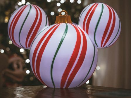A close-up of a festive ornament setup: three striped Christmas balls stacked together, red, white, and green swirls on glossy spheres, holiday vibes.