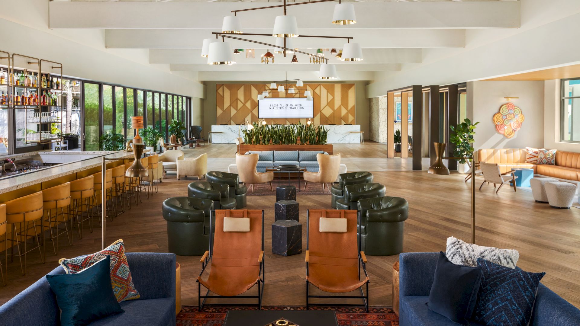 A modern lounge area features various seating arrangements, a bar, and contemporary decor with ample natural light coming from large windows.