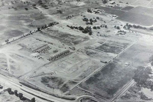 An aerial view of a developing area with partially constructed buildings, roads, and patches of undeveloped land.