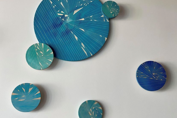 The image shows a wall with six circular art pieces in various shades of blue and teal, featuring intricate linear patterns and abstract designs.