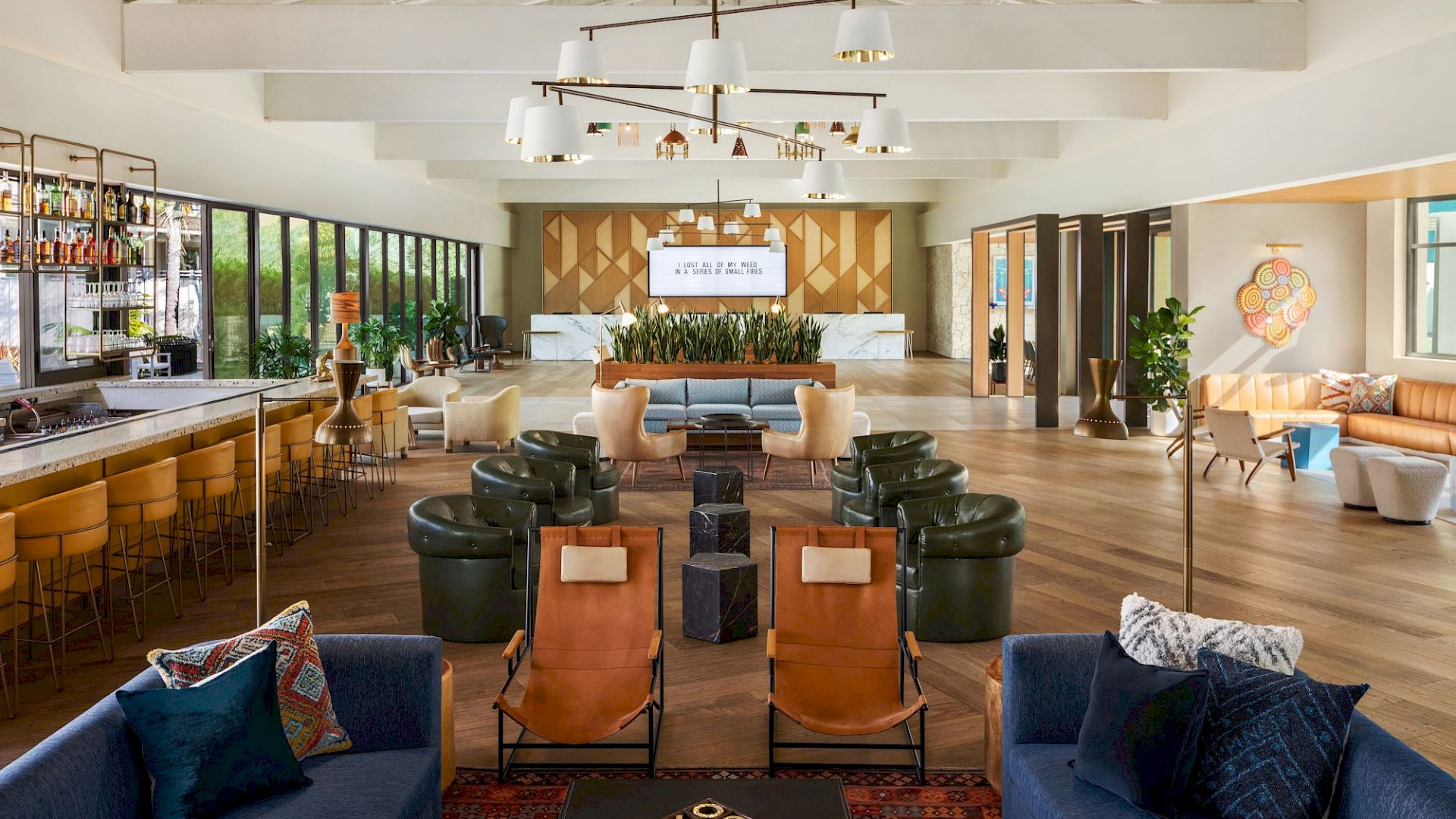 The image shows a stylish, spacious lounge with modern seating, a bar area, large windows, and contemporary decor, featuring a mix of cozy furniture.