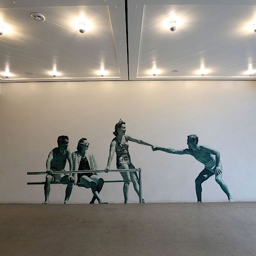 A mural on a white wall depicts four figures, with one reaching out, suggesting a moment of interaction or support, in a minimalistic setting.