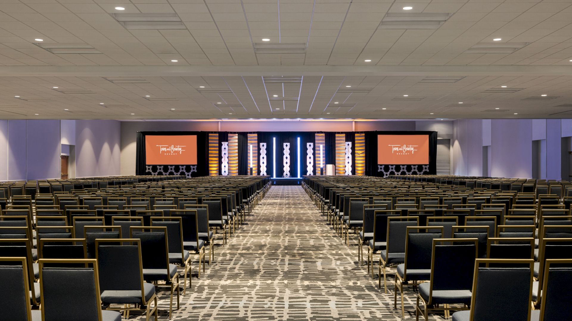 A large conference room with rows of chairs and a stage featuring screens; a Cvent "Top Meeting Hotels" award badge is displayed in the corner. San Diego conference hotel with meeting space.