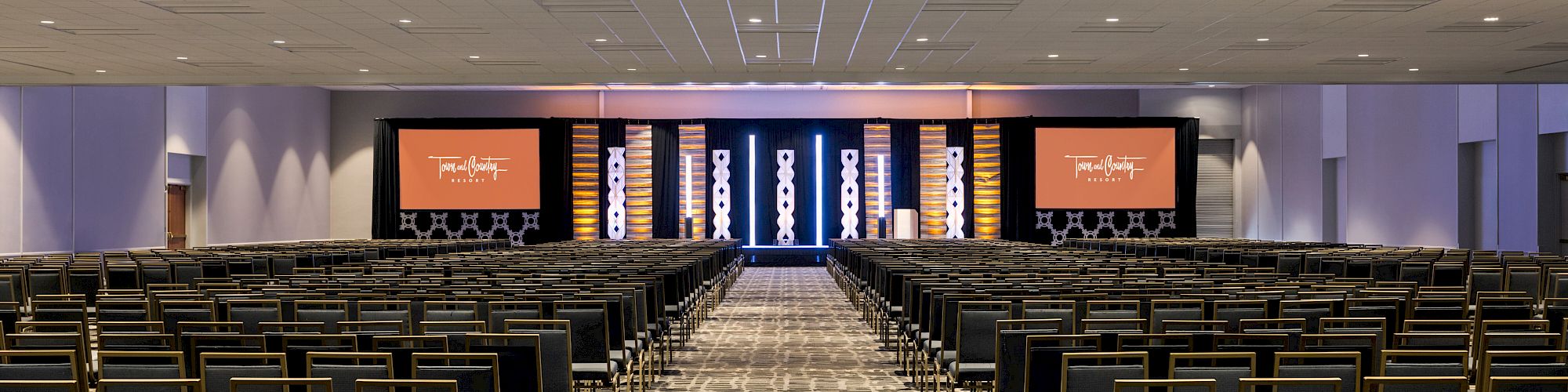 A large conference room with rows of chairs and a stage featuring screens; a Cvent "Top Meeting Hotels" award badge is displayed in the corner. San Diego conference hotel with meeting space.