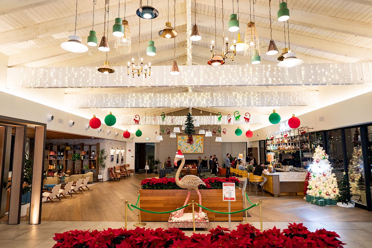A festive indoor hotel atrium with hanging lights, ornaments, a decorated pine, and a giraffe display under the Christmas d&eacute;cor.