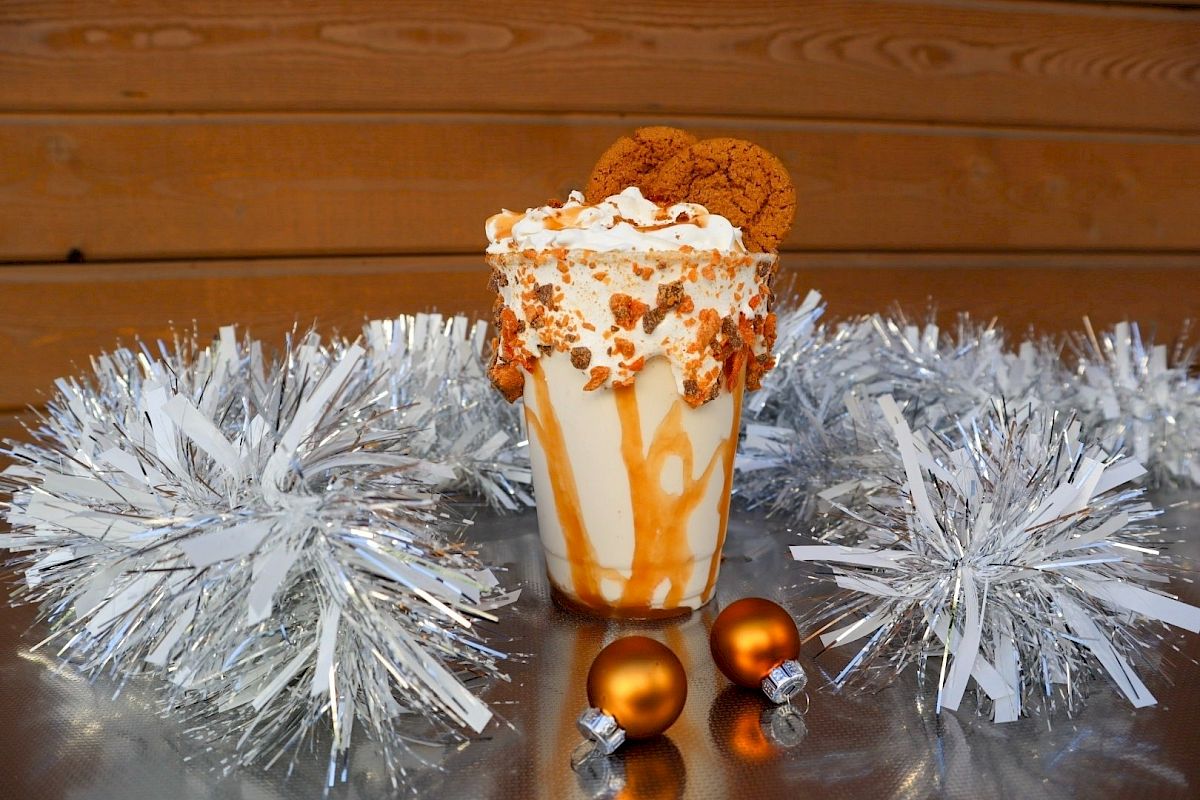 A festive dessert sundae in a glass with whipped cream, cookie crumbs, and silver tinsel decorations.