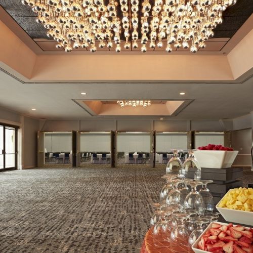A spacious conference room features a grand chandelier, fruit platters, glassware, and a modern sculpture, creating an elegant atmosphere.