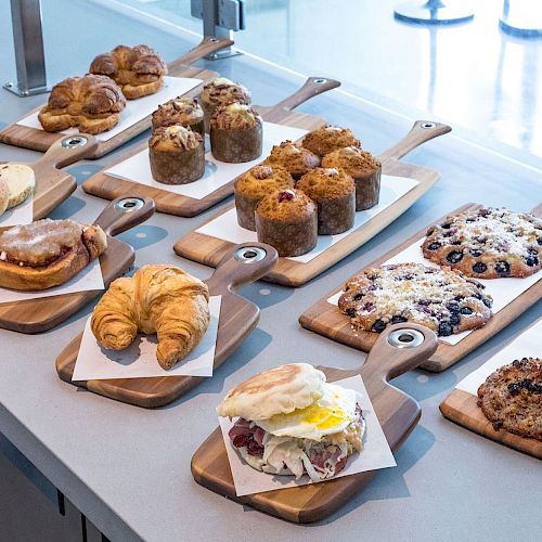 This image shows a variety of baked goods, including croissants, muffins, cookies, sandwiches, and pastries, displayed on wooden boards.