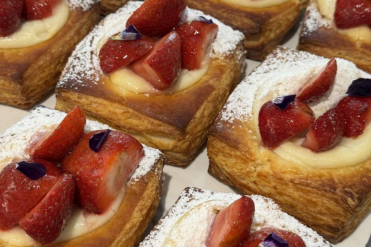 Fresh strawberry pastries with cream filling, topped with strawberry slices and dusted with powdered sugar.