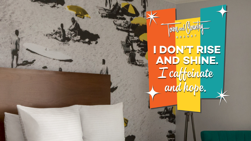 A hotel room with two beds, a vintage wall mural, and colorful posters reading &ldquo;I don&rsquo;t rise and shine, I caffeinate and hope.&rdquo;