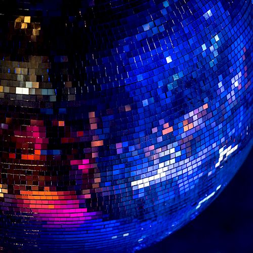 The image shows a close-up of a shiny disco ball reflecting colorful lights in a dark environment.