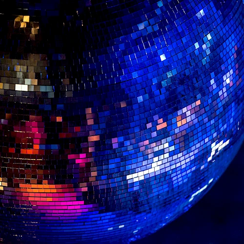 The image shows a close-up of a shiny disco ball reflecting colorful lights in a dark environment.
