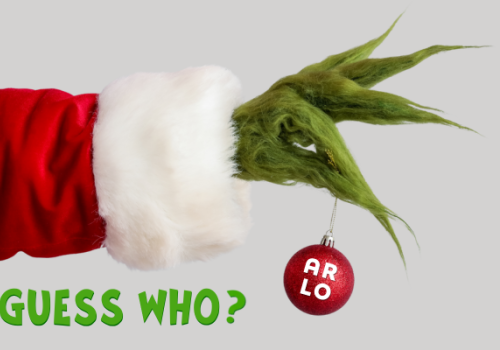 A green, furry hand dressed in red and white holds a red ornament labeled "ARLO." Green text below reads "GUESS WHO?"