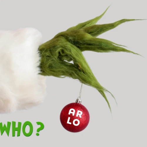 A green, furry hand dressed in red and white holds a red ornament labeled "ARLO." Green text below reads "GUESS WHO?"