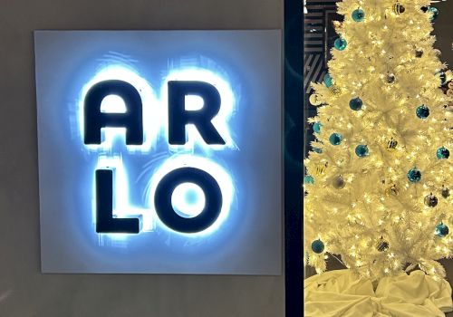 A neon sign reading "ARLO" is on the left, and a white Christmas tree with blue ornaments is on the right.
