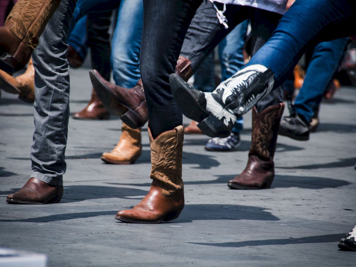 People wearing cowboy boots are dancing in a group, likely engaged in a line dance or similar activity.