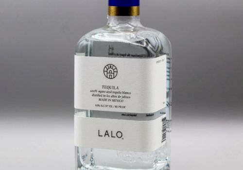 This image shows a bottle of LALO tequila, featuring a white label and a gold cap with a blue stripe, set against a neutral background.