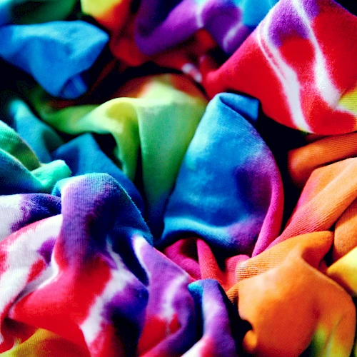 A colorful tie-dye fabric is crumpled, showcasing vibrant patterns and hues of blue, red, green, and orange in the image.