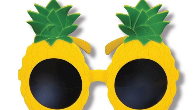 A pair of novelty sunglasses designed to look like pineapples, featuring yellow frames and green leafy tops.